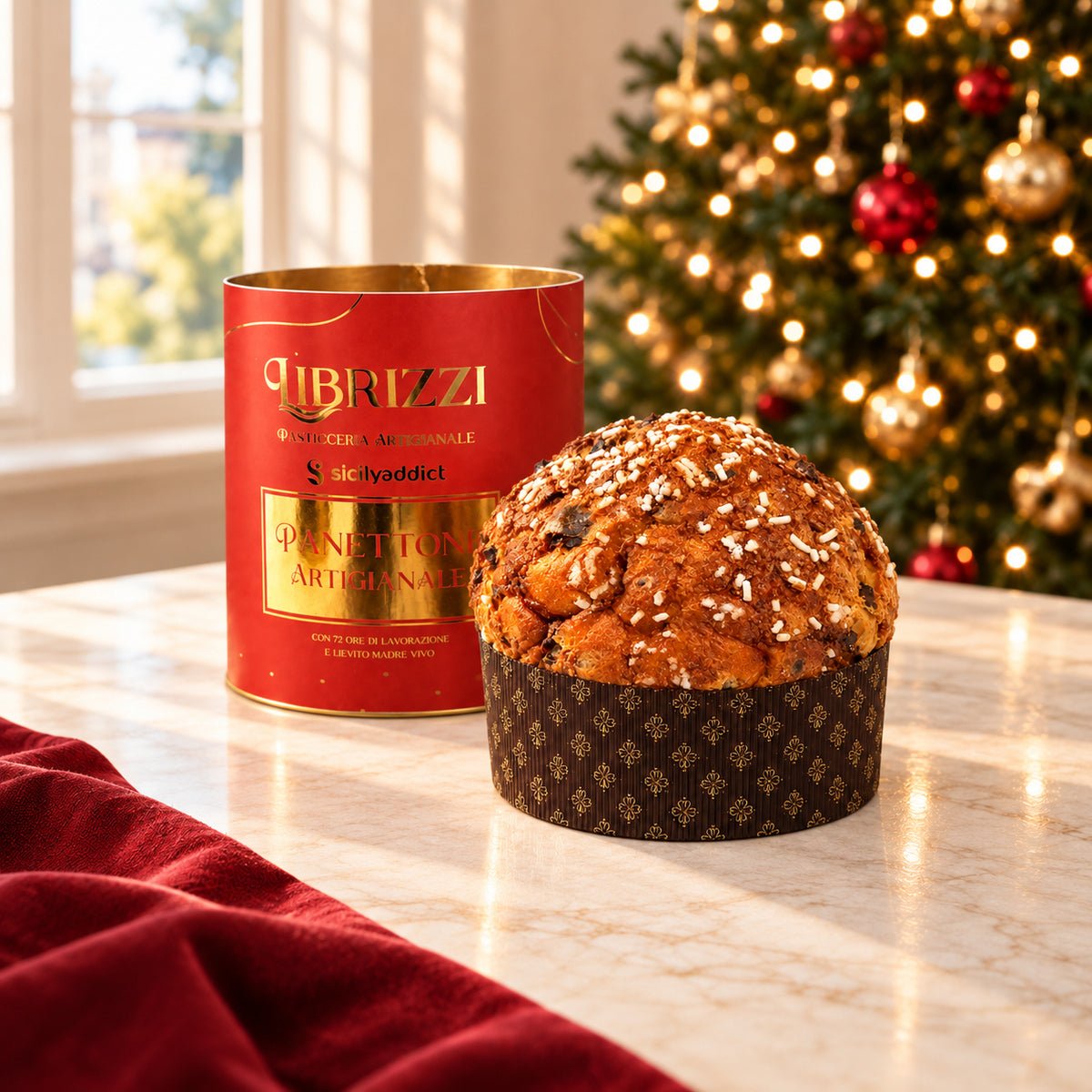 Panettone albicocca e cioccolato Librizzi Deluxe di SicilyAddict, intero con confezione rossa in ambiente natalizio