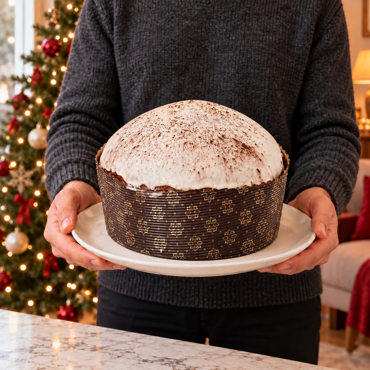 Panettone al Tiramisu' tenuto in mano davanti alla tavola natalizia.