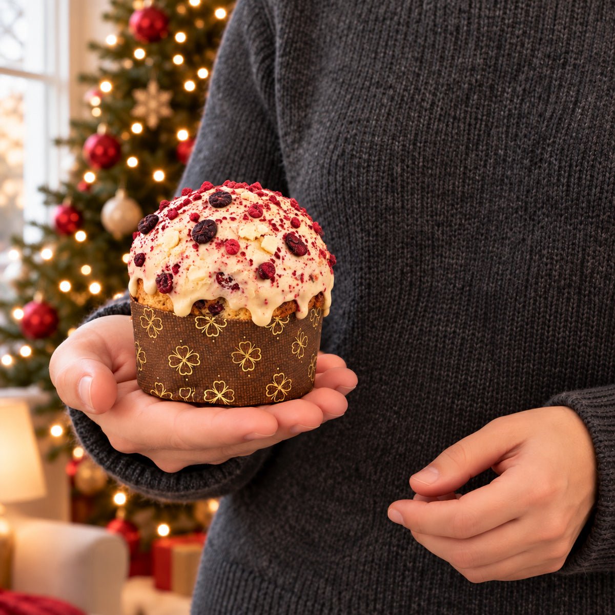 Panettoncino Frutti di Bosco e Cioccolato Bianco tenuto in mano davanti alla tavola natalizia.