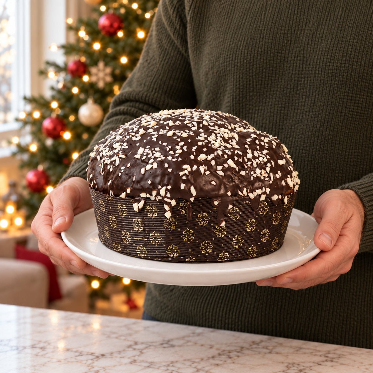 Panettone ai Tre Cioccolati tenuto in mano davanti alla tavola natalizia.