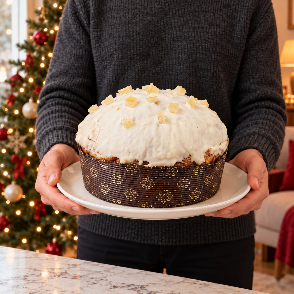 Panettone Limone e Cioccolato Bianco tenuto in mano davanti alla tavola natalizia.